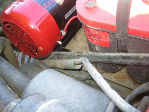 1990 Ford Bronco - red ExtremeAire compressor sits next to a red plastic fluid reservoir above hoses and a casting in an engine bay.