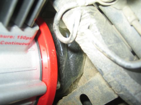 1990 Ford Bronco - Red-collared portable air compressor reading '150psi Continuous' next to taped harness wiring in a dusty engine bay.