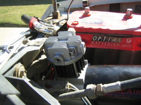 1990 Ford Bronco - silver-headed air compressor mounted beside a red Optima battery in a vehicle engine bay, with cables and air line attached.