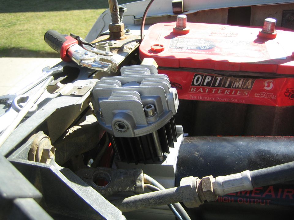 Mounted air compressor next to red Optima battery in an engine bay