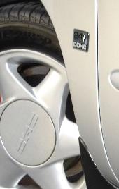 1999 Ford Taurus - Detail of a car's wheel and fender, a '24V DOHC' badge and 'SuperMotors' watermark.