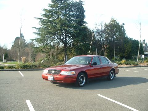 1999 Ford Crown Victoria - This red 1998 Ford Crown Victoria sedan is parked in a lot, viewed from the front three-quarter angle.
