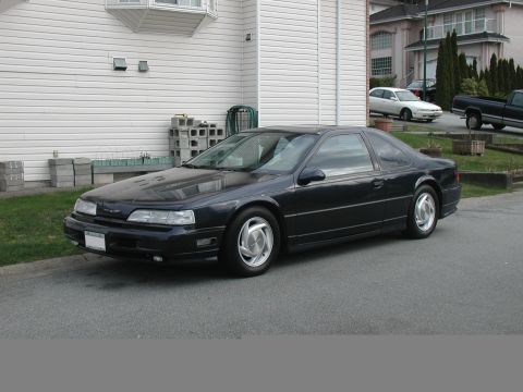 1990 Ford Thunderbird - A dark blue 1990 Ford Thunderbird is parked on a residential street, viewed from the front three-quarter angle.