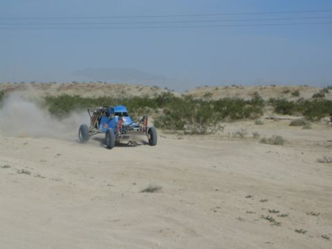 Blue off-road buggy turning on a sandy desert track
