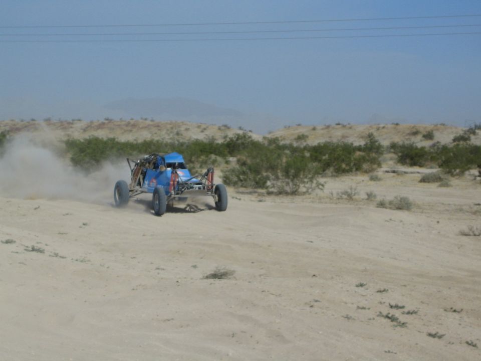 Blue off-road buggy turning on a sandy desert track
