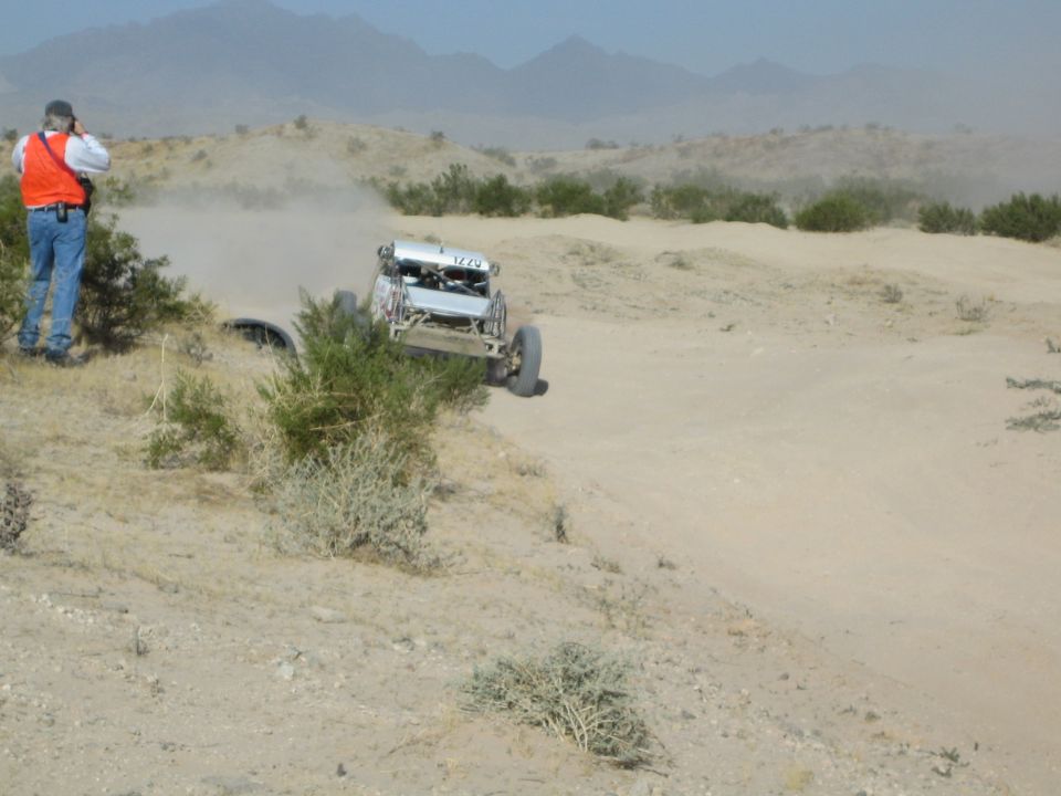 Spectator watches a desert buggy crest a rise on a dusty course