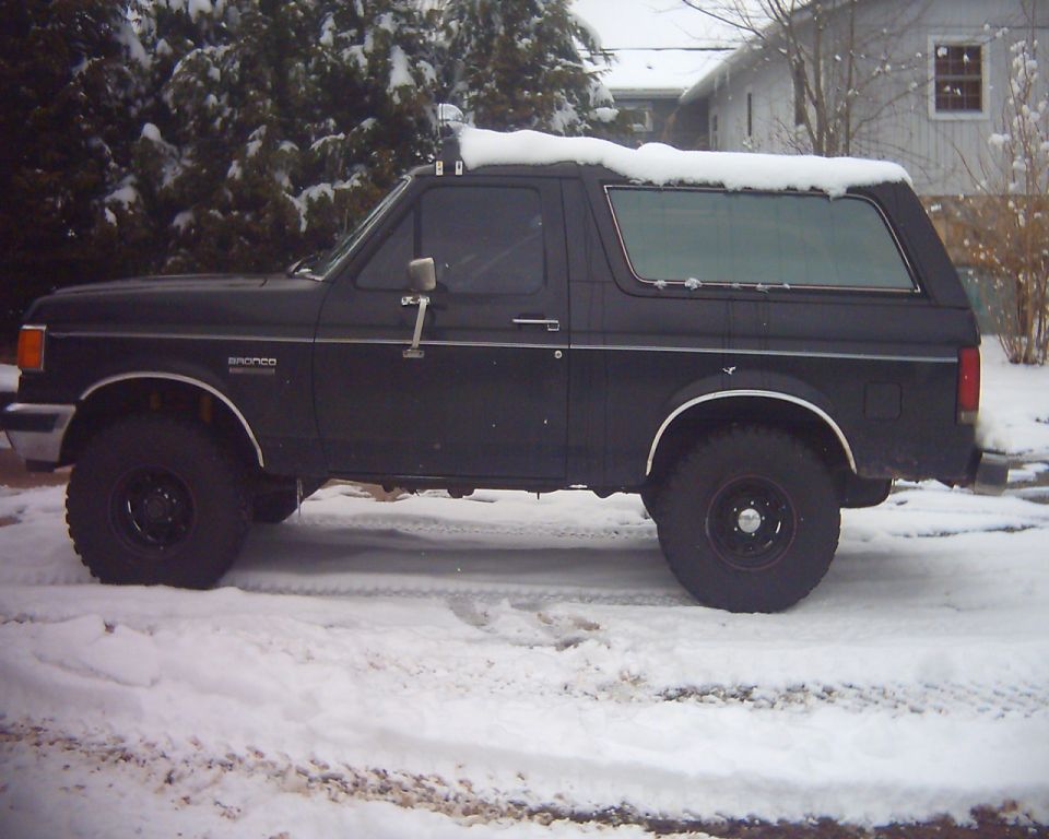Black 1987 Ford Bronco parked in snow, side view
