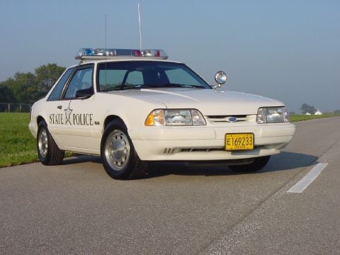 1993 Ford Mustang - A white 1993 Ford Mustang police car is seen from a three-quarter front view on a paved road.
