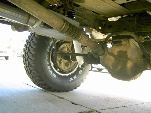 1988 Ford Bronco - Close-up view of the rear axle and suspension components on a lifted SUV, showing a large off-road tire.