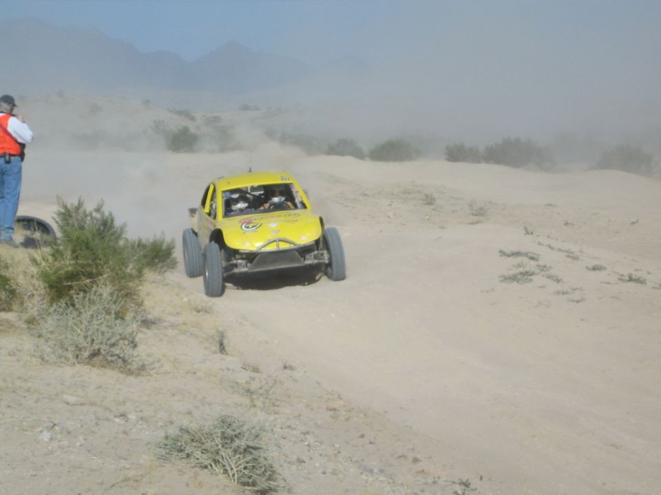 Yellow off-road race truck speeding along a dusty desert course