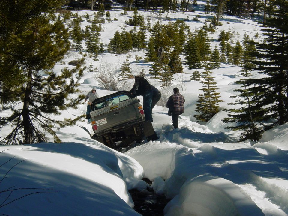 Truck stuck in deep snow, people trying to push it out