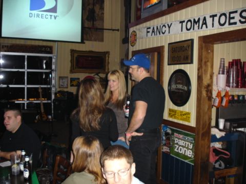 1985 Ford Crown Victoria LTD - People socialize in a bar with a DIRECTV screen and bar signage in the background.