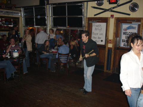 1985 Ford Crown Victoria LTD - A group of people are socializing in a bar, with one man holding drumsticks.