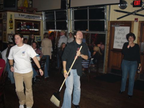 1985 Ford Crown Victoria LTD - A group of people are inside a bar, with one person holding a broom.