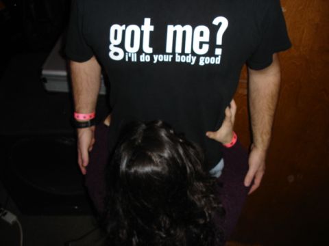 1985 Ford Crown Victoria LTD - A person wears a t-shirt with a provocative message, with another person's head resting against them.