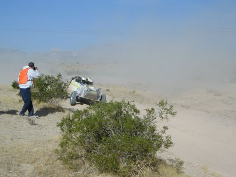 White off-road buggy crossing desert as a photographer shoots from a ridge