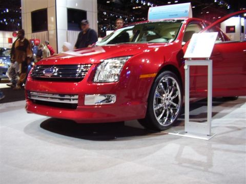1997 Ford Taurus - A red Ford sedan is displayed with its door open, custom chrome wheels.