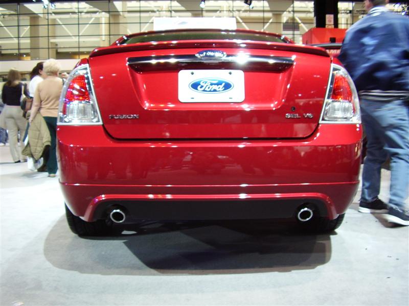 Rear of a red Ford Fusion with dual exhaust pipes and a Ford badge on the trunk