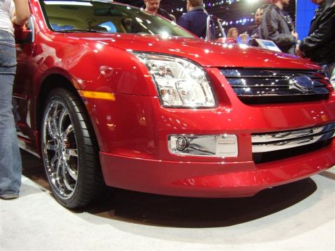 1997 Ford Taurus - Front view of a red car with a chrome grille and distinctive headlights at an auto show.