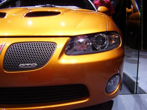 1997 Ford Taurus - Front view of an orange 2004 Pontiac GTO at an auto show, its distinctive grille and hood scoops.
