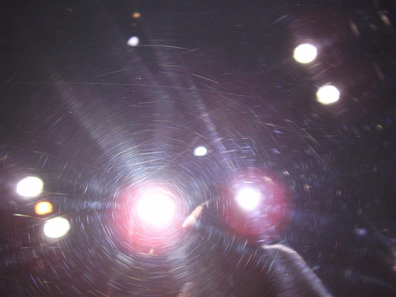 swirl marks on dark car paint, lights reflecting