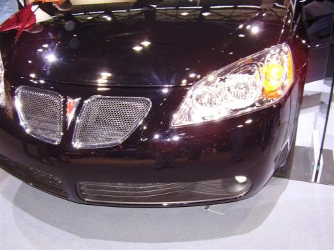 1997 Ford Taurus - The front of a dark red Pontiac G6 is visible, showing its distinctive grille and headlights.