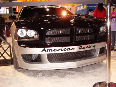 1997 Ford Taurus - A black and silver car with "American Racing" text is displayed at an auto show.