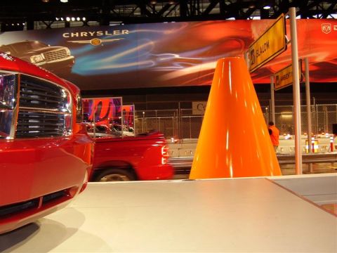 1997 Ford Taurus - A red pickup truck is displayed at an auto show with a Chrysler banner overhead and a large orange cone.
