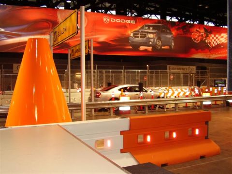 1997 Ford Taurus - A silver sedan is displayed at an indoor event, with a large Dodge advertisement visible in the background.