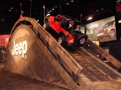 1997 Ford Taurus - A red Jeep Wrangler navigates a simulated off-road obstacle course at an auto show.