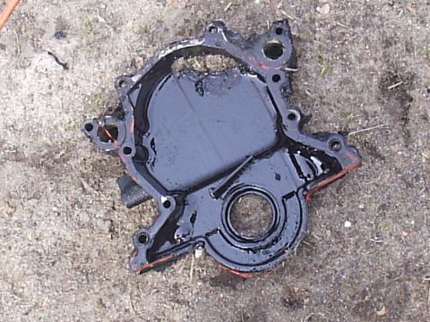 1989 Ford Bronco - Water pump housing, likely removed from an engine, lies on a concrete surface with visible gasket material.