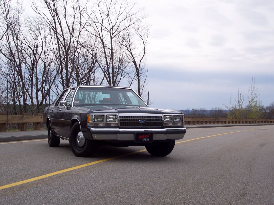 Black Ford Crown Victoria sedan on steel wheels with D.A.R.E. front plate, 3/4-front view