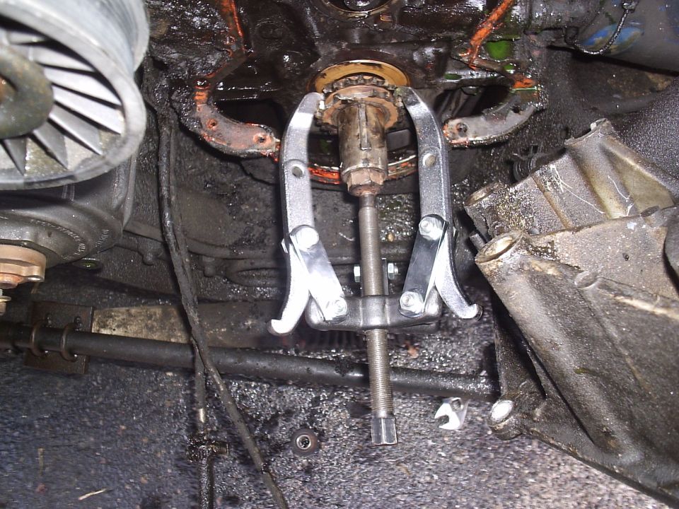 Jaw puller mounted on an engine crankshaft snout during front-end disassembly