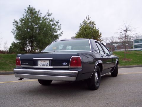 2001 Ford Crown Victoria - This 2001 Ford Crown Victoria sedan is viewed from the rear, showing its dark paint and chrome accents.