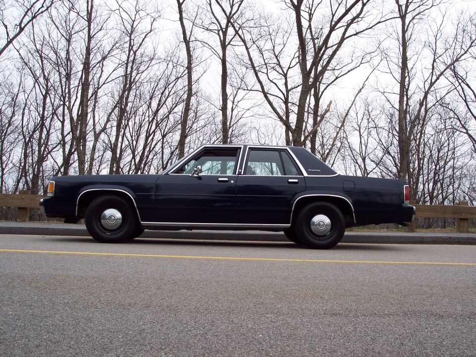 Side view of a dark blue 2001 Ford Crown Victoria parked on a roadside