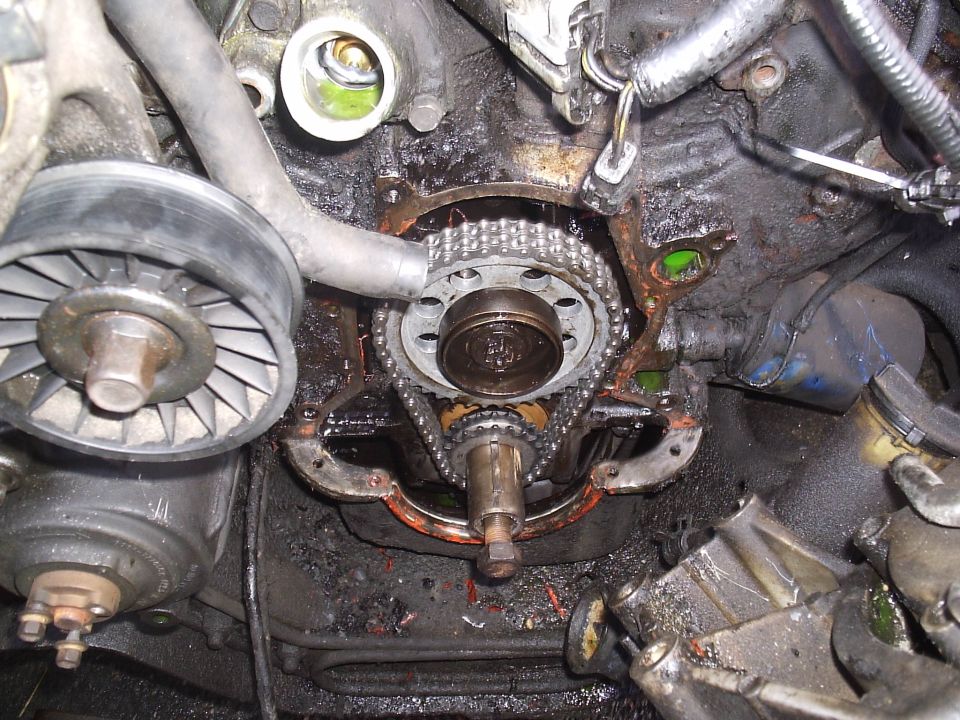 Engine front with timing cover removed showing timing chain and sprockets on a dirty block