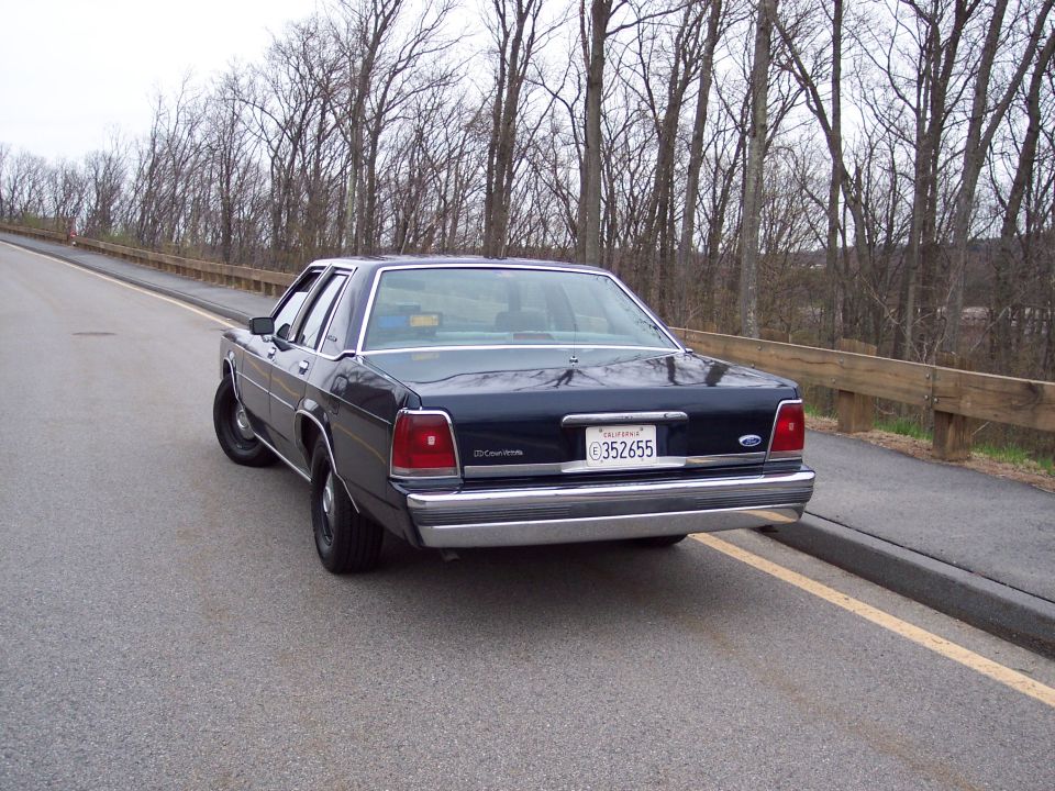 Dark blue 2001 Ford Crown Victoria sedan parked on the side of a road, rear view