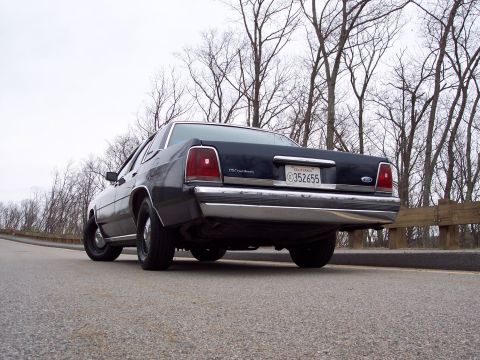 2001 Ford Crown Victoria - Rear view of a dark 2001 Ford Crown Victoria, showing its distinctive taillights and chrome bumper.