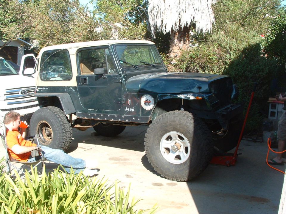 Dark green Jeep YJ with tan hardtop, lifted with large tires