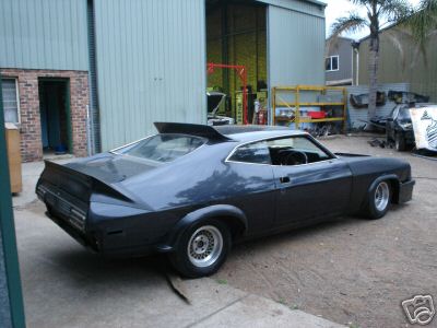 1972 Ford Ranchero - 1972 Ford Ranchero with custom spoiler and aftermarket wheels sits outside a workshop.