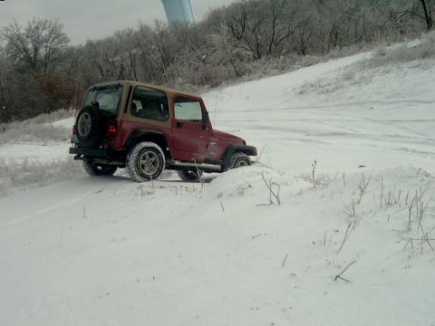 1998 Jeep TJ - A red 1998 Jeep TJ navigates a snowy incline, its off-road capability.