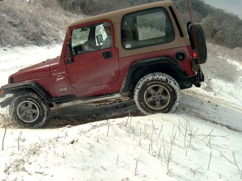 1998 Jeep TJ - A red 1998 Jeep TJ navigates a snowy incline, its off-road capability.