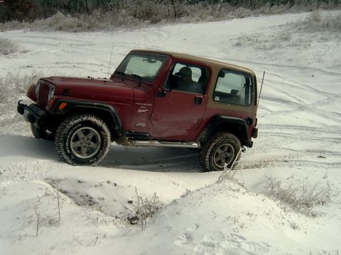 1998 Jeep TJ - Red 1998 Jeep TJ Wrangler navigates a snowy terrain.