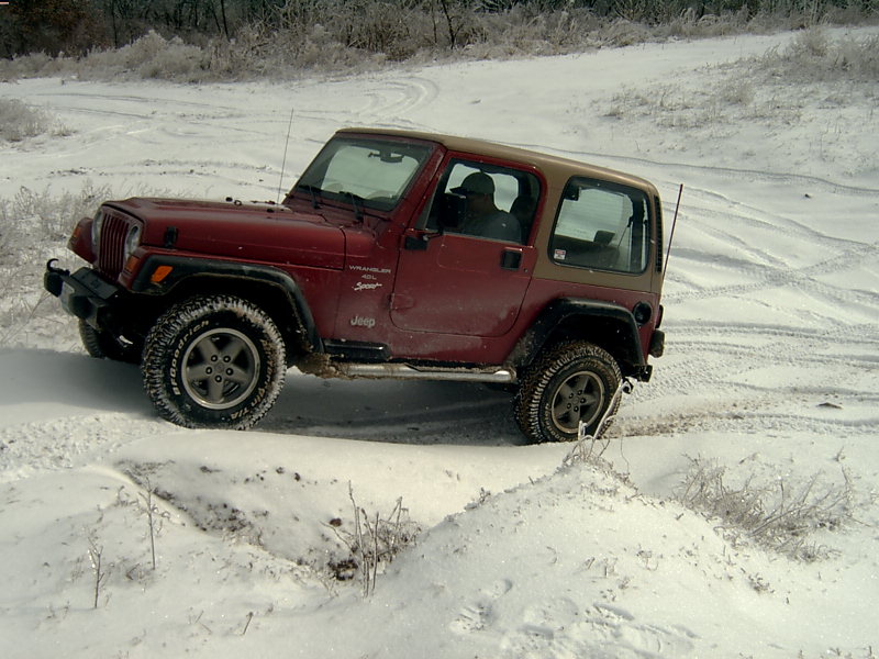 1998 Jeep TJ Wrangler driving in snow, red body with tan top