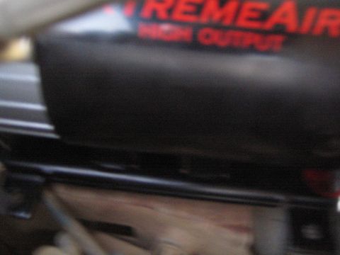 1990 Ford Bronco - blurry close-up of an ExtremeAire High Output air compressor body showing the red and white lettering on black.
