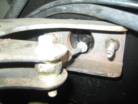 1990 Ford Bronco - close-up of a metal bracket with an adjustable threaded linkage rod and bolts mounted to a vehicle component.