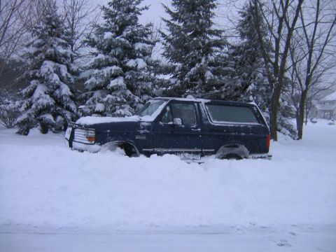 1994 Ford Bronco - A 1994 Ford Bronco is partially buried in snow, with only its side visible.