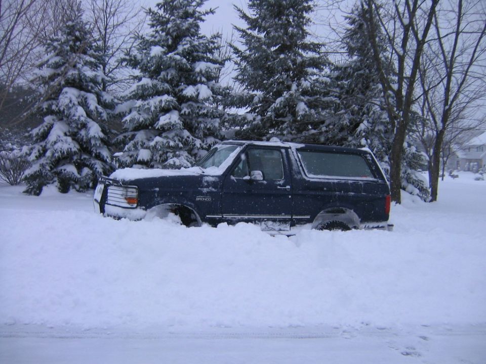 Dark blue 1994 Ford Bronco stuck in snow, side view