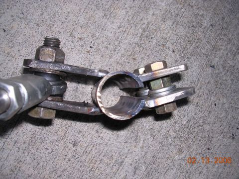 1994 Ford Bronco - A close-up view of a fabricated metal bracket assembly, bolts and nuts, on a concrete background.