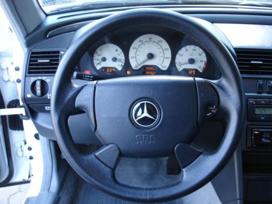 Mercedes-Benz steering wheel with tri-star logo and three-dial gauge cluster behind